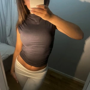 SNYGG TAJT TOPP - Säljer en snygg grå ärmlös topp från Gina Tricot i storlek XS. Toppen är tight och har en hög hals. Perfekt för både skola och middag!😇