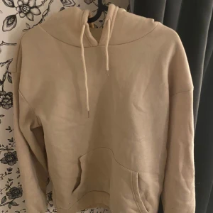 Beige hoodie med fjärilstryck - Säljer en superfin beige hoodie i storlek xs . Den har en stor ficka fram och en mysig huva med dragsnören. På baksidan finns ett coolt tryck med texten 'Butterfly Rose' och bilder av fjärilar och en ros. Perfekt för höst och vinter när man vill vara både varm och stilren. 🦋🌹