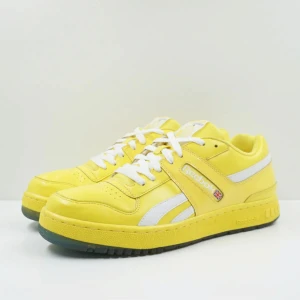 Reebok classic Kool-aid lemonade - Ett par gula reebok sneakers med vita detaljer och snörning. Skorna har en glad smiley och texten 'Kool-Aid' på sidan. Sulan är genomskinlig med en blå text och smiley under.