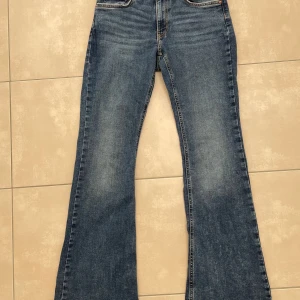 Jeans bootcut - Säljer dessa jättefina jeans från Gina Tricot i strl 38, som jag endast har använt ett fåtal gånger. Jeansen är utsvängda och har en lågmidjad passform, innerbenssömmen är 82 cm.  