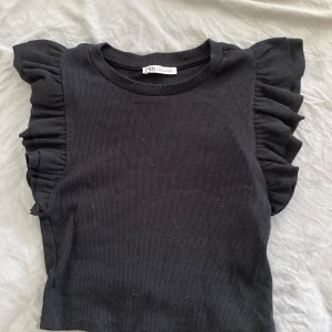 Svart volang topp - Svart ribbad topp med volang ärmar