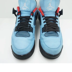 Jordan 4 retro travis scott cactus jack - Ett par Jordan 4 retro travis scott cactus jack i ljusblått och svart med röda detaljer. Skorna har en svart sula med en röd Jumpman-logotyp på undersidan. De har snörning och en hög ankelkrage för extra stöd. Lite använd 7/10 orginal box och hang tag inkluderas.