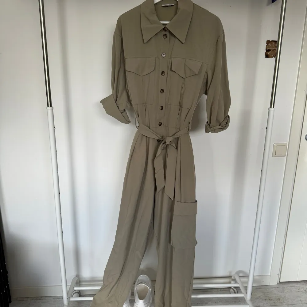 Säljer en jumpsuit/byxdress från Topshop i storlek 38 EU (M)! Sparsamt använd. Jumpsuiten stängs med knappar och kan  knytas i midjan med ett avtagbart bälte.  (Köparen står för frakt). Toppar.