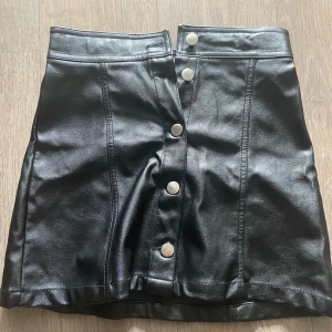 Tight svart läder kjol med silver knappar😽, snygg och lätt att styla  - 36 cm lång  38 cm bred 