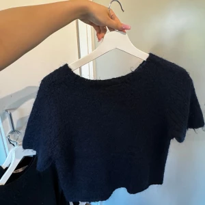 Svart kortärmad topp - En svart kortärmad topp med en mjuk och fluffig textur. Toppen har en rund halsringning och är något croppad i modellen.
