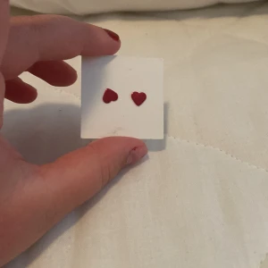 Röda hjärtformade örhängen - Ett par små röda hjärtformade örhängen. Perfekta för att lägga till en söt och romantisk touch till din outfit.