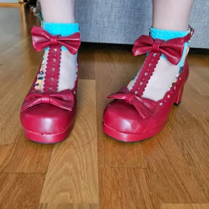 Lolita skor - Röda klackar med hjärtan och rosetter. Finns några bucklor på sidan men annars är de knappt använda, säljer för att de är för stora.