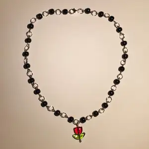 Vackert pärlhalsband av svarta porslins pärlor och röd glas-tulipan. Nytt, oanvänt och handgjort. Kontakta gärna vid frågor och innan köp☺️