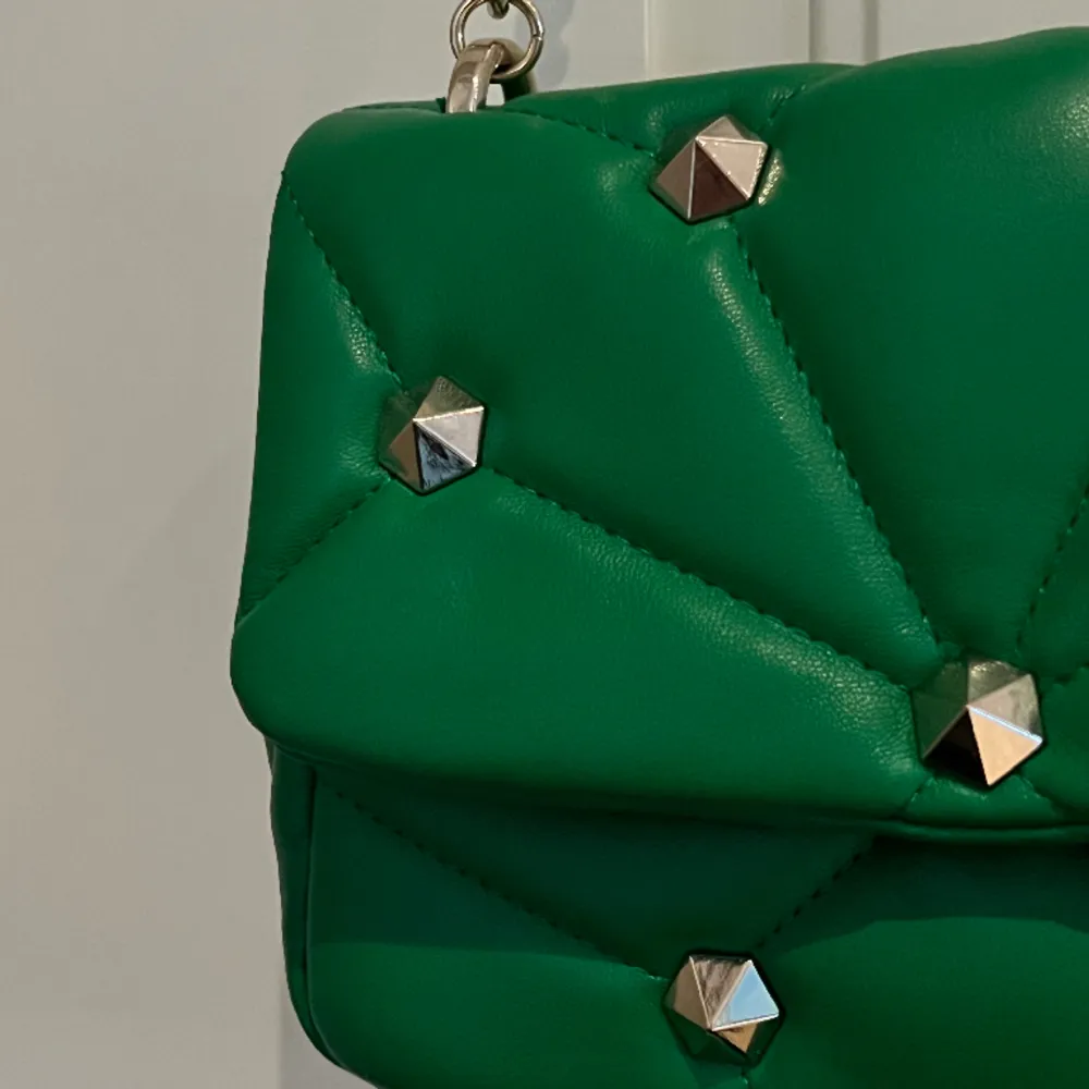 Grön axelremsväska med nitar ifrån zara, perfekt för att uppgradera en basic outfit. Använd en gång, kedjan är i nyskick utan defekter💚🤙🏻🤙🏻. Väskor.