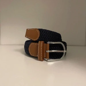 flätat bälte - marinblå - Snyggt och trendigt flätat bälte. Bältet är elastiskt och går därför att spänna åt till passform