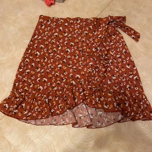 Blommig omlottkjol - En kort omlottkjol från Gina Tricot! Den har ett hål så man ser resåren på insidan (tredje bilden) men det påverkar inte hur den sitter/ser ut när man har på sig den. man kan enkelt sy ihop det om man vill 🩷