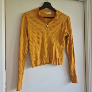 Croppad polotröja  - Croppad polotröja i musturd. Half zipper. Mjuk och skön.