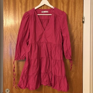 Klänning - Rosa klänning med volanger, knytning vid armarna. Använd fåtal gånger