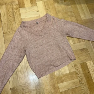 Stickad tröja  - Ljusrosa stickad tröja från Nelly, lite kortare och med v-krage 