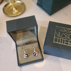 Big Claw örhängen från Maria Nilsdotter  - Säljer mina fina Big Claw örhängen( par), köptes 2017 i Maria Nilsdotter butiken på Sturegatan i Stockholm . Säljs inte längre i just detta utförande med lila pärla, men finns med vit pärla i butik( se bild). 