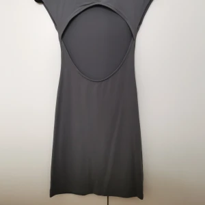 Kort klänning med öppen rygg - Oanvänd kort klänning med öppen rygg i mjukt tyg.