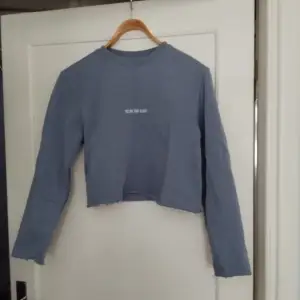 Blå croppad sweatshirt med texten 
