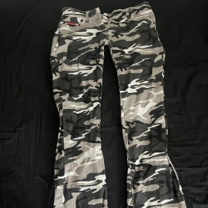 Lågmidjade bootcut jeans i grå-svart kamouflagemönster  - Snygga och i bra skick. Säljer för att de är lite för små för mig. Det är storlek 36 och jag är 170 cm lång för referens.