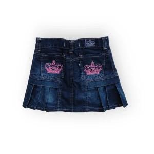 Victoria Beckham for Rock and Republic jeans kjol - Mörk jeanskjol med rosa kronor och rhinestones. Midja: 31cm, Längd: 30 cm. Bra skick, inga tydliga defekter förutom att några stenar har fallit av. Fråga gärna om fler bilder 💕