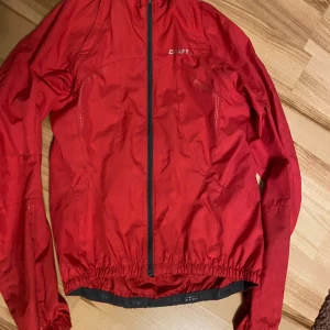 Jacka cykling/löpning Craft  - Avtagbara ärmar så jackan kan användas som väst. Skyddar mot vind och måttligt regn. Rymlig ficka på ryggen.  Tyvärr har den fläckar på en ärm efter ett kedjebyte (se sista bilden), därav det låga priset.