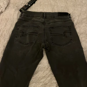 Lågmidjade gråa jeans - lågmidjade gråa jeans ifrån junkyard. Säljer eftersom de är för stora för mig i midjan! Nästan för långa så de är nere över fötterna på mig som är 168! Lite lite slitningar längst ner på jeansen då de varit för långa men inget märkvärdigt!