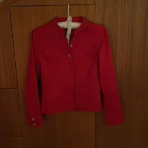 Röd jeansjacka - Skitcool röd jeansjacka med coola detaljer, har en slita baktill och knäpps med knappar! Bra skick😊skriv för fler bilder!