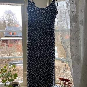 Oanvänd midiklänning från Hollister, vita blommor på svart botten. XS. Lätt att justera med knytband över axlarna