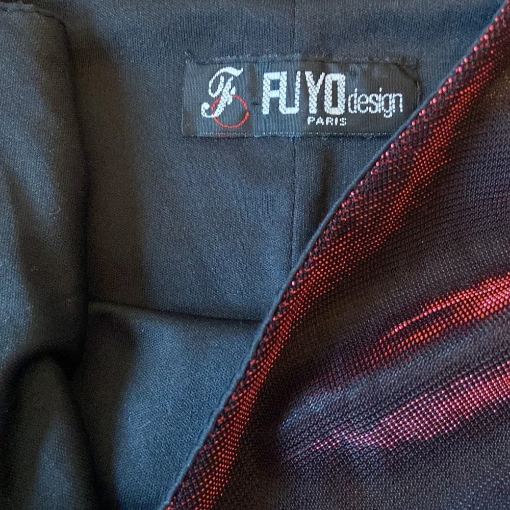 Röd-svart klänning i glansigt material, från ”Fujo design”. Färgen i bild 2 stämmer inte riktigt överens med hur klänningen ser ut i verkligheten. Bra skick förutom några ”trådar” i tyget, skriv för bilder på det! 😽. Klänningar.
