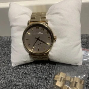 Marc Jacobs klocka - Orginalpris: 2 498. Jättesnygg Marc Jacobs klocka från serien Baker i bra skick. Borstat/polerat guldtonat stål och mineral glas. Diametern är 36mm och tjockleken är 10mm. Batteriet behöver bytas ut vilket enkelt går att fixa på ur&pen.