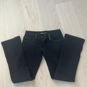 Lågmidjade jeans - Svarta jeans med coola detaljer, säljer då de är för små för mig. Midjemått: 34cm och innerbenslängd: 71cm💗