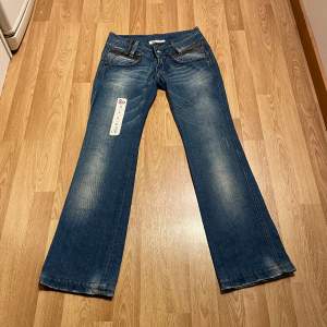 (4) lågmidjade bootcut jeans med detaljer på fickorna. Midjemått rakt över: 34 cm, innerbenslängd: 79 cm 🩵