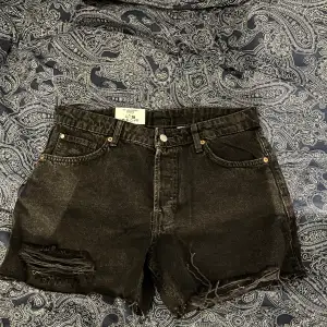 Ett par svarta shorts i storlek 36. Helt oanvända med prislappar kvar. Jätte dåligt ljus men dem är svarta!.