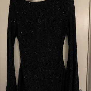 Klänning - Glittrig klänning med öppen rygg i storlek S. Använd en gång. Kort i modellen. Sitter superfint på och är så bekväm.
