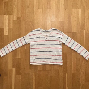 Stickad Pippitröja från ginatricot i stl XS - Stickad pippitröja i vitt med röda och blåa ränder och knyt i halsen. Tröjan är sparsamt använd, men små fläckar förekommer, se bild 3. Klicka gärna på köp nu och meddela för eventuella frågor. :)