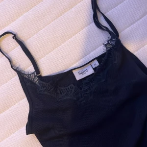 Marinblått linne med spets - Jättefint, marinblått, ribbat linne från saint tropez. Ganska lång modell. Jättefint spets längs bröstet. Används inte och därför säljer jag det