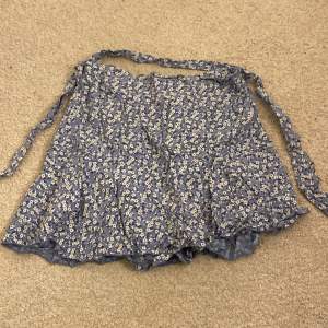 En blommig ljusblå kjol med inbyggda shorts. Kommer ursprungligen från en marknad utomlands. Använder ett fåtal,  gånger. Insydd i midjan också men går lätt att sprätta 