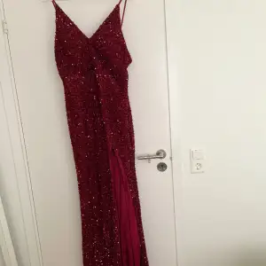 Maxi klänning i vinröd/röd med paljetter/glitter. Har slits vid benet och etikett på