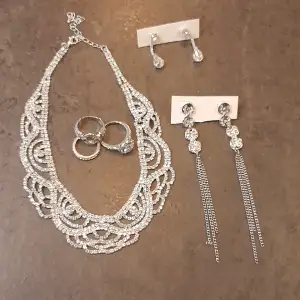 Smycken i silverfärg och strass Nyskick  Halsband 2 par örhängen 3 ringar olika storlek  Estimerat värde: 600kr