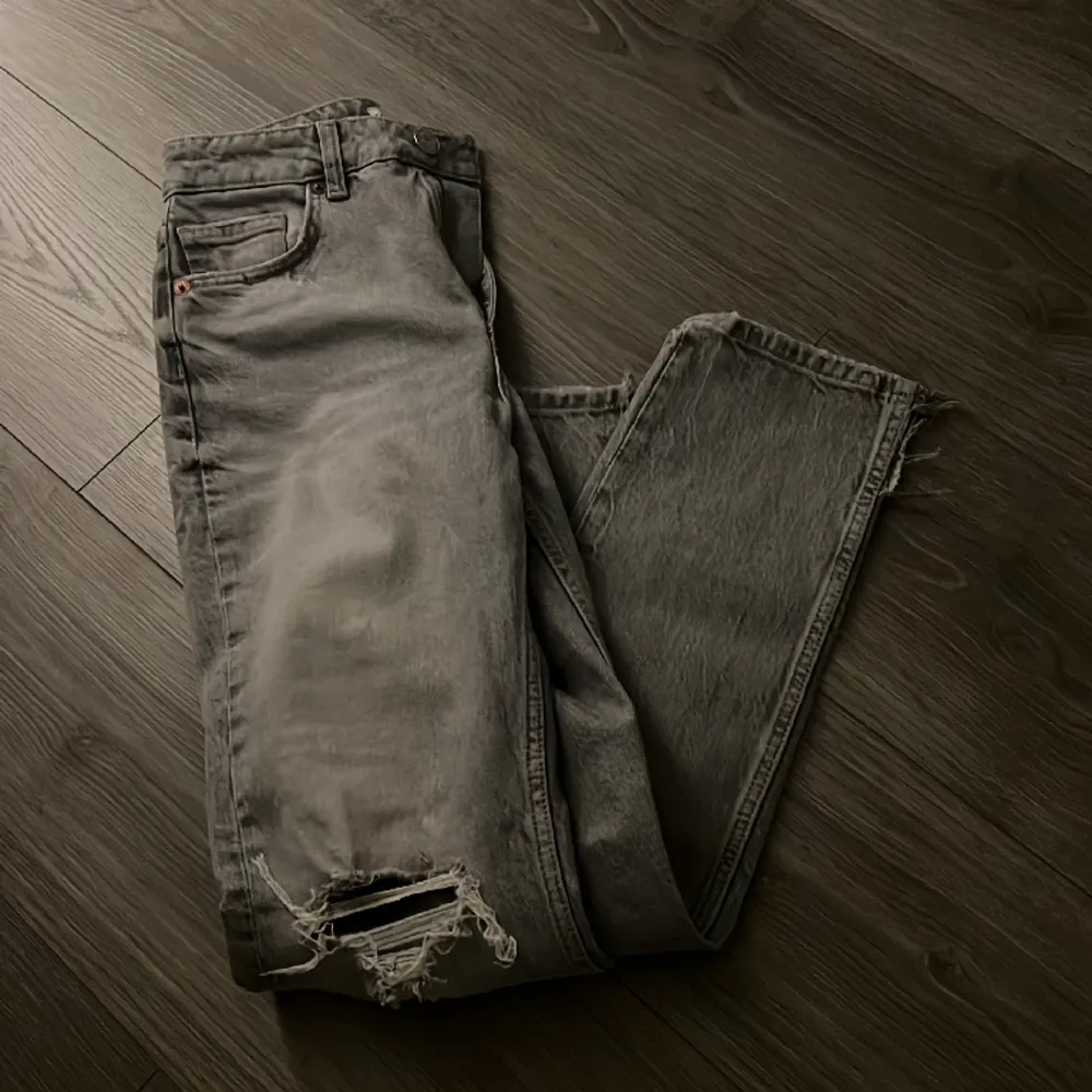 Grå jeans med hål vid knäna å liten slits där nere, strl 36. Jeans & Byxor.