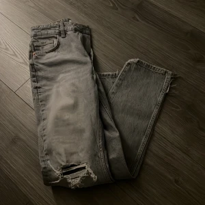 Zara jeans grå  - Grå jeans med hål vid knäna å liten slits där nere, strl 36