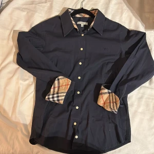 Mörkblå burberry skjorta - Fet mörkblå burberry london skjorta i stl XS. Inga synliga deffekter använt fåtal gånger. Säljer pga den inte passar mig längre.