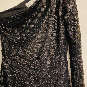 Svart glittrig långklänning - Jättefin svart glittrig långklänning med en arm. Paljettdetaljer runt hela klänningen och den går ned till marken. Köpt som balklänning men var tyvärr för liten🖤
