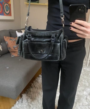 Axelremsväska  - Väska köpt second hand med både ett långt band och korta. Väldigt praktisk med många fack! 30x20 cm