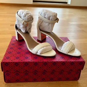 Tory Burch högklackade skor  - Ett par vita klackskor med guld detalj. Aldrig använda och kommer i sin originalförpackning.  5cm klack 