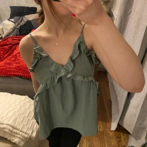 linne - jättefint grönt linne med volanger. Öppen rygg och går att justera banden☺️