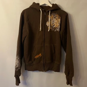 Brun hoodie  - Brun hoodie med flera olika detaljer. Märke: Billabong. Storlek: S