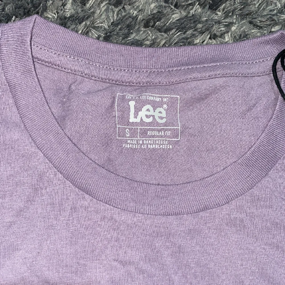 Lilafärgad t-shirt från Lee i regular fit med bröstficka. Oanvänd med prislapp kvar. Inga skador eller annat fel . Nypris 299!. T-shirts.