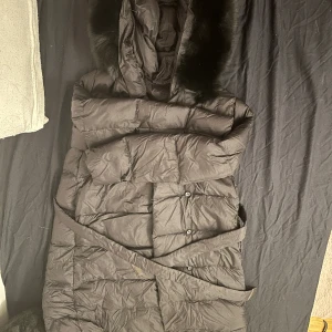 LILLY DUNJACKA SVART - Lång svart jacka, bra skick, oanvänd, 100 % äkta päls samt äkta dun 86%-90% Kom gärna med bud!