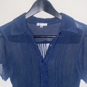 Marinblå blus - Tunn blus med krage och knappar. Marinblå. See through. Kortärmad.