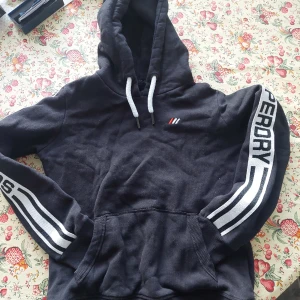 SUPERDRY  TJOCK FLEECE HODDIE  - Storlek: 40 Fleece fodrad Tjock modell kraftiga snörning vid hals och magficka 